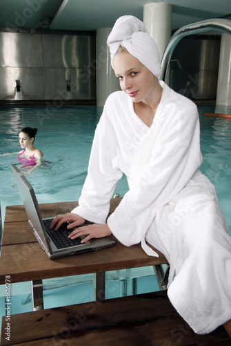 Photo: Woman on computer next to a swimming pool Woman on computer next to a swimming pool
