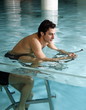 Young man on exercise bike in spa pool