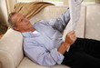 Foto: Mature man reading newspaper on couch Mature man reading newspaper on couch