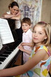 Mother looking at her children playing piano