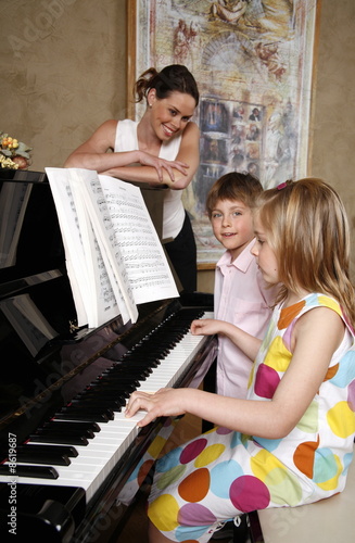 Photo: Mother looking at her children playing piano Mother looking at her children playing piano
