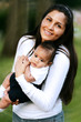 Young Mother Rocking Baby Outside in the Park Young Mother Rocking Baby Outside in the Park