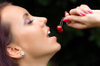 Foto: The girl tasting a cherry The girl tasting a cherry