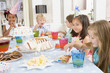 Photo: Young children at party sitting at table with food smiling Young children at party sitting at table with food smiling