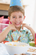 Young boy at party sitting at table with food smiling