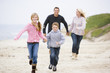 Photo: Family running at beach holding hands smiling Family running at beach holding hands smiling