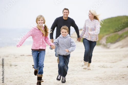 Foto: Family running at beach holding hands smiling Family running at beach holding hands smiling