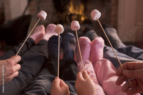 Foto: Feet warming at a fireplace with marshmallows on sticks Feet warming at a fireplace with marshmallows on sticks