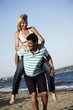 Photo: Mature adult couple piggyback on beach *** Local Caption *** A mature couple enjoying a romantic holiday... Mature adult couple piggyback on beach *** Local Caption *** A mature couple enjoying a romantic holiday...