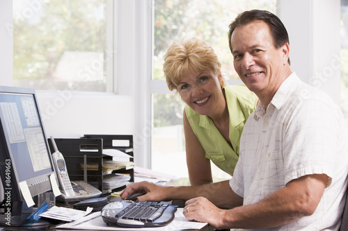Photo: Couple in home office at computer smiling Couple in home office at computer smiling