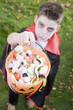 Young boy outdoors wearing vampire costume on Halloween holding