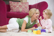 Mother in living room with baby eating banana and smiling