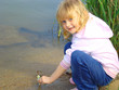 Photo: Little girl on the riverside. Game and fun. Little girl on the riverside. Game and fun.