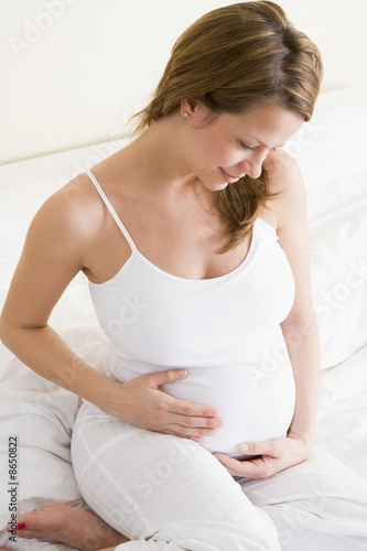 Pregnant woman sitting in bed smiling