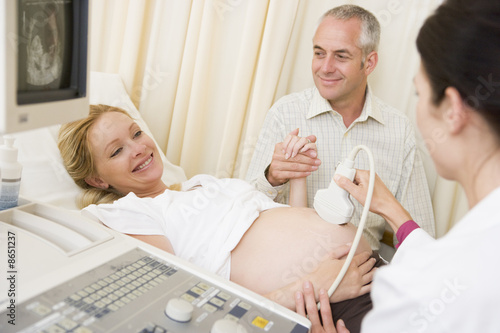 Photo: Pregnant woman getting ultrasound from doctor with husband watch Pregnant woman getting ultrasound from doctor with husband watch
