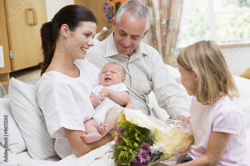 Photo: New mother with baby and family in hospital smiling New mother with baby and family in hospital smiling