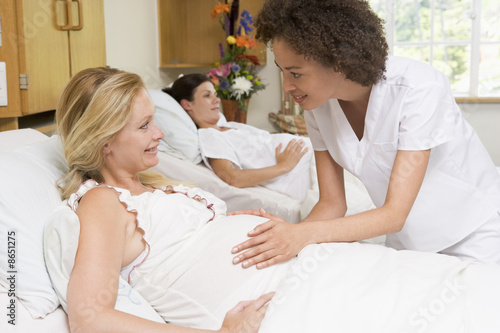 Foto: Nurse checking pregnant woman's belly and smiling Nurse checking pregnant woman's belly and smiling