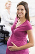 Pregnant woman at work holding belly smiling