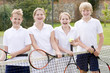 Foto: Four young friends with rackets on tennis court smiling Four young friends with rackets on tennis court smiling
