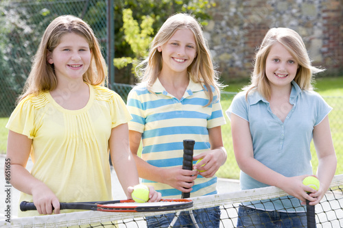 Girl Friends on Photo  Three Young Girl Friends With Rackets On Tennis Court Smiling