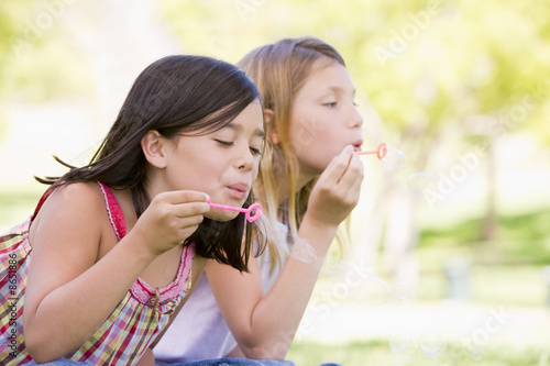 Photo: Two young girls blowing bubbles outdoors Two young girls blowing bubbles outdoors