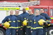 Portrait of a group of firefighters by a fire engine