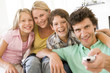 Photo: Family in living room with remote control smiling Family in living room with remote control smiling