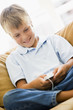 Young boy in living room with MP3 player smiling Young boy in living room with MP3 player smiling