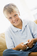 Young boy in living room with MP3 player smiling Young boy in living room with MP3 player smiling
