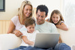 Family In Living Room With Lap...