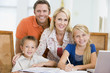 Couple helping two young children with laptop do homework in din