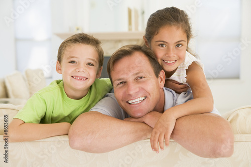 Photo: Man and two young children sitting in living room smiling Man and two young children sitting in living room smiling