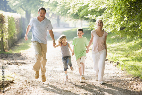 Photo: Family running outdoors holding hands and smiling Family running outdoors holding hands and smiling