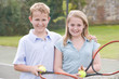 Foto: Two young friends with rackets on tennis court smiling Two young friends with rackets on tennis court smiling