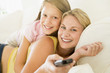 Photo: Woman and young girl with remote control embracing on sofa smili Woman and young girl with remote control embracing on sofa smili