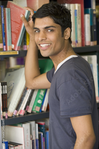 Photo: Male college student reaching for a library book Male college student reaching for a library book