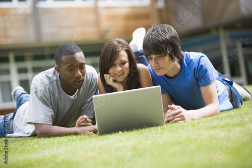 Photo: College students using laptop on campus lawn, College students using laptop on campus lawn,