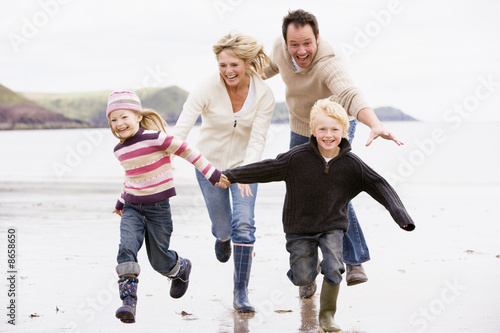 Photo : Family running on beach holding hands smiling Family running on beach holding hands smiling