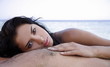 Young woman on man's chest on beach