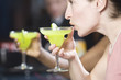 Photo: Side view of a young woman drinking a cocktail. Side view of a young woman drinking a cocktail.
