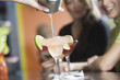 Close up of a hand pouring cocktail in a glass.