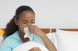 Girl 7-9 blowing nose in bed