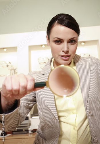 Photo: Woman with magnifying glass in store Woman with magnifying glass in store