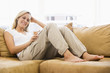Woman in living room listening to MP3 player smiling Woman in living room listening to MP3 player smiling