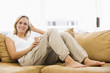 Woman in living room listening to MP3 player smiling Woman in living room listening to MP3 player smiling