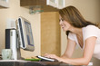 Photo: Woman in kitchen with computer smiling Woman in kitchen with computer smiling