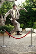 Businessman in garden jumping over barrier