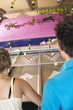 Teenage couple playing horse racing game in amusement park