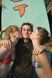 Two female teenagers kissing male teenager on cheek