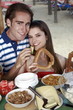 Young adult couple at breakfast holding sesame bread ring and melon
